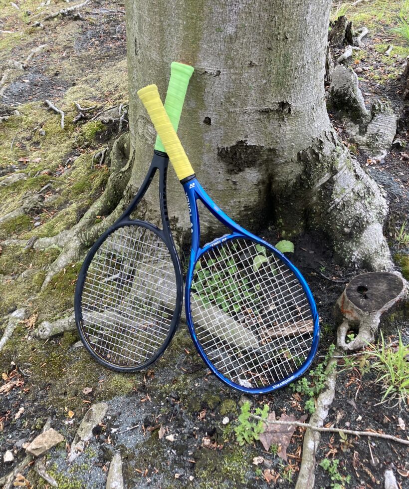 Two tennis rackets lean on a tree
